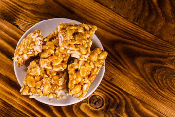 Ceramic plate with peanut brittles on wooden table. Top view