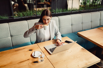 Beautiful businesswoman enjoying a coffee in front of her laptop computer