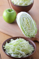 Cabbage, chopped cabbage in a clay bowl on a wooden background, green apple, vegetarianism, green apple and green cabbage, rustic style, chinese cabbage with fruit, minimalism