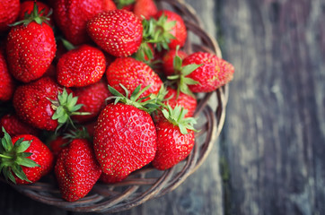 Strawberry in wicker plate on wooden background