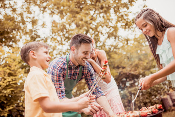 Family having a barbecue party, standing around the grill