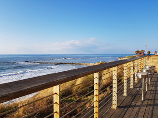 Obraz premium Empty chairs on Promenade with view on Seashore of Mediterranean sea on sunny day. Concept of tourism ,vacation and relax .