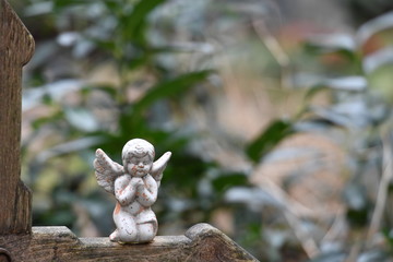 Little angel sitting on a wooden christian cross