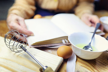 Open recipe book in the hands of an elderly woman