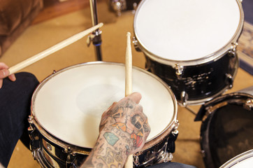 Fototapeta na wymiar Closeup on drummer tattooed hand and sticks 