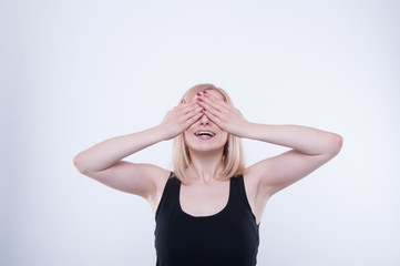 Pretty woman is closing her eyes with hands and smiling. Young girl isolated on white background.