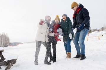Full length portrait of two young couples laughing happily having fun outdoors throwing snow, copy space