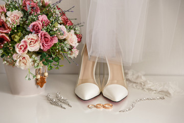 Bridal accessories for luxury wedding day. Marriage concept. Wedding and engagement ring near shoes...