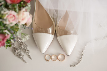Wedding shoes for bride near one engagement ring and two wedding rings for bride and groom. Marriage concept