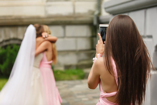 Wedding blogger make photo of bride and bridesmaid who having fun after wedding ceremony. Happy marriage concept