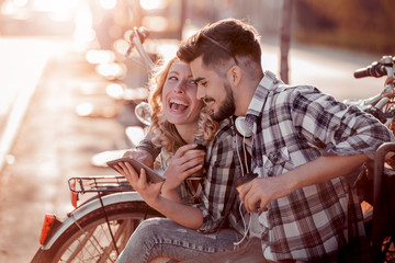 Couple in love enjoy together on a bench with bikes.