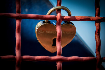 gold glänzendes Schloss in Herzform am Zaun