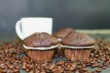 Dark muffins, cups of coffee and coffee beans on black background. Black copy space. Coffee bar concept