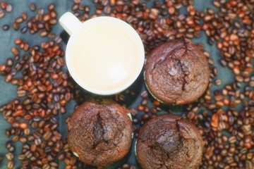 Dark muffins, cups of coffee and coffee beans on black background. Flat design. Coffee bar concept
