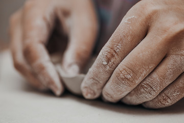 Female potter works with clay, craftsman hands close up, kneads and moistens the clay before work