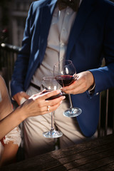 Close up portrait of a female and male couple hands toasting with glasses of red wine