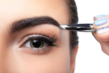 Young woman correcting eyebrow shape, closeup