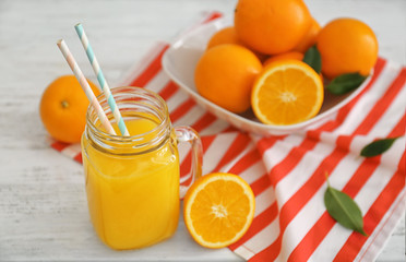 Mason jar with fresh orange juice and fruit on wooden table