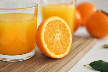 Glass with fresh orange juice and fruit on wooden board