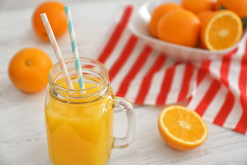 Mason jar with fresh orange juice and fruit on wooden table