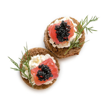 Fototapeta Delicious canapes with black caviar on white background