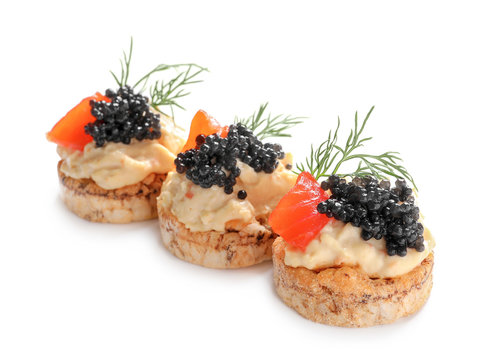 Delicious canapes with black caviar on white background