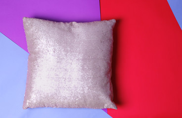 Shiny decorative pillow on colorful background