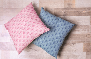 Two stylish pillows on wooden floor