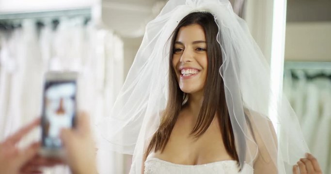 4K Happy bride to be having her photo taken during a dress fitting in wedding gown store. Slow motion.