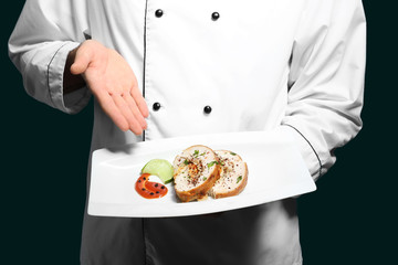 Male chef holding plate with tasty dish, closeup