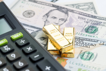 Success investment or financial wealth calculation concept, gold bars / ingot on pile of money US dollar banknotes with calculator