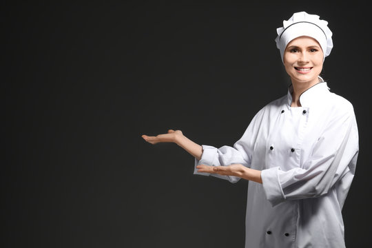 Female chef in uniform on black background