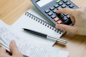 Cost calculation or bill payment concept, hand put finger on calculator and black pen on paper...