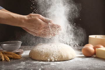 Femme frappant des mains et saupoudrant de farine sur de la pâte fraîche sur la table