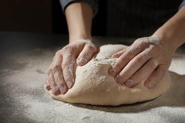 Woman kneading dough on table, closeup
