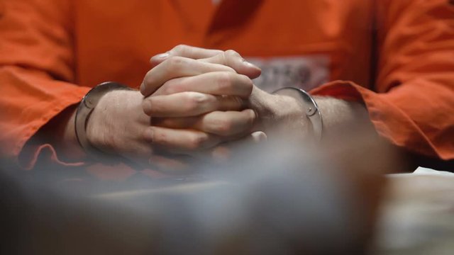 Prisoner giving evidence in interrogation room, detective writing testimony