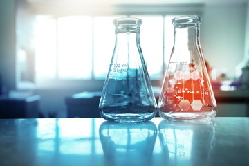 two orange red and blue flask with chemical structure in research science laboratory background