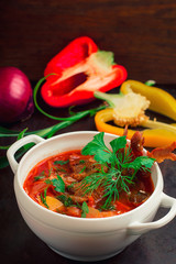 Borscht with meat and greens on the white plate. Traditional Ukrainian Russian red soup. Old black rustic background. Top view