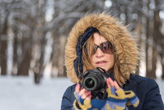 Portrait Of A Woman Holding A Digital Camera In The Woods In Winter