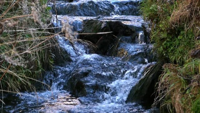Autumn river, closeup slow motion view of a small river, in a autumn color landscape, on a sunny fall day, on simplon pass, in the alps of Switzerland