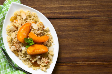 Couscous dessert with apricots, yellow raisins, coconut flakes and cinnamon, photographed overhead with natural light (Selective Focus, Focus on the top of the dessert)