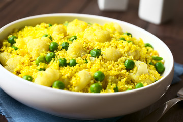 Couscous mit Erbsen, Blumenkohl, Ingwer und Curry in Schüssel, fotografiert mit natürlichem Licht (Selektiver Fokus, Fokus in die Mitte des Gerichts)