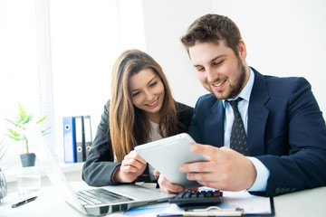 Fototapeta premium Young businessman discussing something with his colleague, and using a digital tablet together