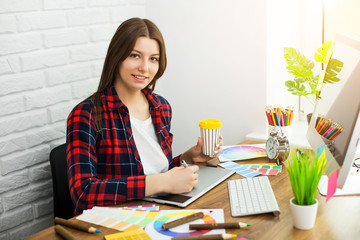 Beautiful young designers discussing ideas and smiling while working in office