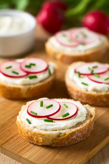 Brotscheiben mit Frischkäse, Radieschen und Schnittlauch, fotografiert mit natürlichem Licht (Selektiver Fokus, Fokus auf die Vorderkante der Radieschenscheiben auf dem ersten Brot)