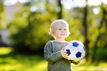 Fototapeta premium Little boy having fun playing a soccer game on sunny summer day