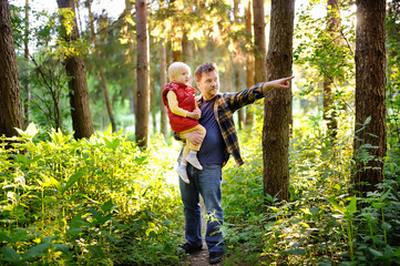 Father and his little son during the hiking activities in forest at sunset