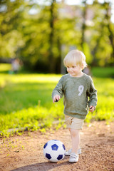 Little boy having fun playing a soccer/football game on summer day