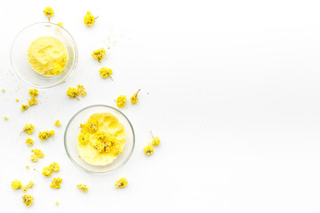 Aromatic spa salt. Yellow spa salt with delicate spring flowers on white background top view copy space