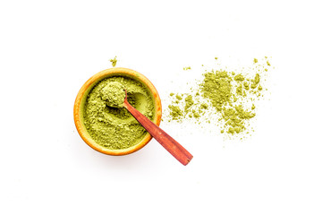 Powdered matcha green tea in bowl and scattered on white background top view copy space